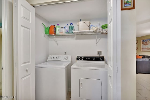 clothes washing area featuring washing machine and clothes dryer and tile patterned floors