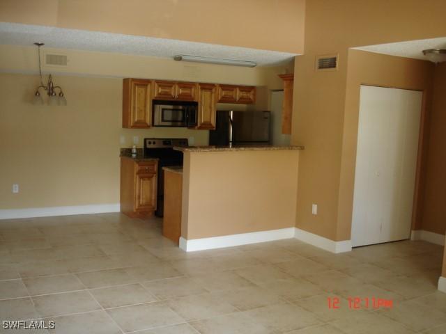 kitchen with black fridge, electric stove, light tile patterned flooring, and hanging light fixtures