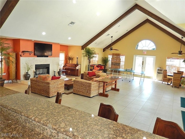 living room with ceiling fan, high vaulted ceiling, light tile patterned flooring, french doors, and beamed ceiling