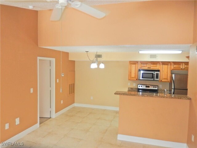 12571 Equestrian Cir Unit 902, Fort Myers, FL 33907 - kitchen with stainless steel appliances, dark stone countertops, ceiling fan, and a peninsula