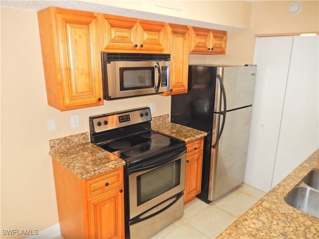 12571 Equestrian Cir Unit 902, Fort Myers, FL 33907 - kitchen featuring appliances with stainless steel finishes, light tile patterned flooring, and light stone countertops