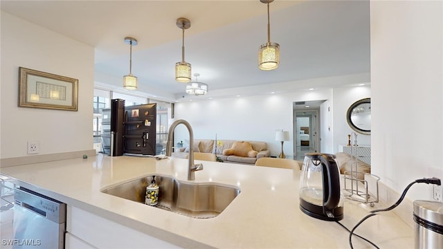 kitchen featuring hanging light fixtures, sink, stainless steel dishwasher, and white cabinets