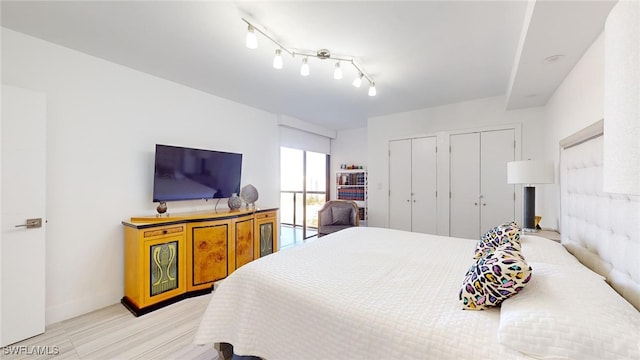 bedroom featuring two closets and track lighting