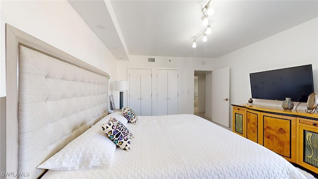 bedroom with track lighting and two closets