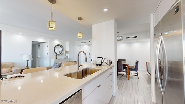 kitchen with appliances with stainless steel finishes, decorative light fixtures, sink, and white cabinets