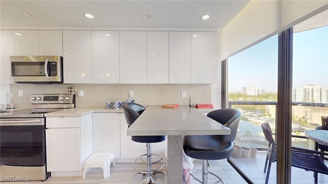 kitchen featuring white cabinetry, a breakfast bar area, kitchen peninsula, and appliances with stainless steel finishes