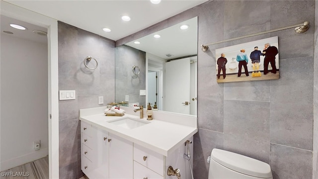 bathroom with vanity, wood-type flooring, tile walls, and toilet