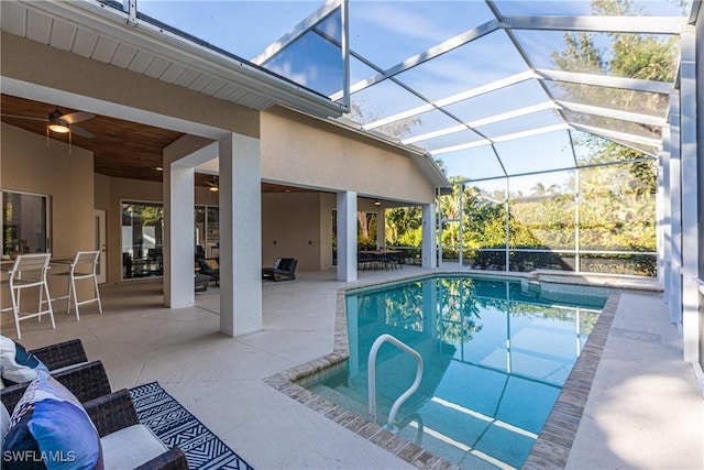 view of swimming pool with ceiling fan, an outdoor living space, a lanai, and a patio area