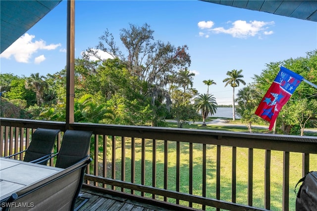 wooden terrace with a water view and a yard