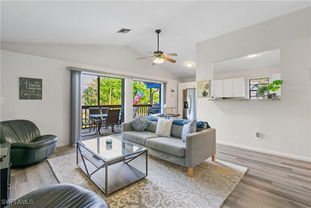 living room featuring ceiling fan, lofted ceiling, and light wood-type flooring