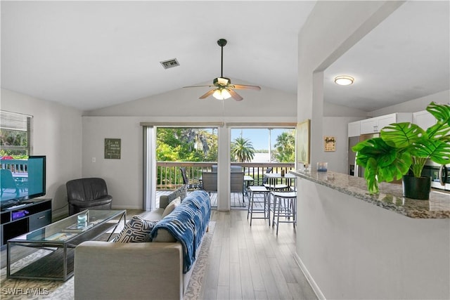 living room featuring lofted ceiling, light hardwood / wood-style floors, and ceiling fan