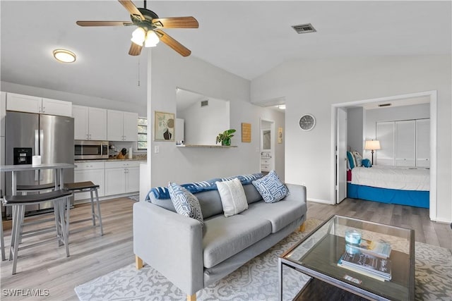 living room with vaulted ceiling, light hardwood / wood-style floors, and ceiling fan