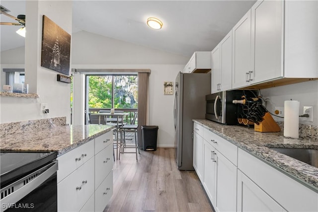 kitchen with white cabinetry, light stone countertops, stainless steel refrigerator, and lofted ceiling