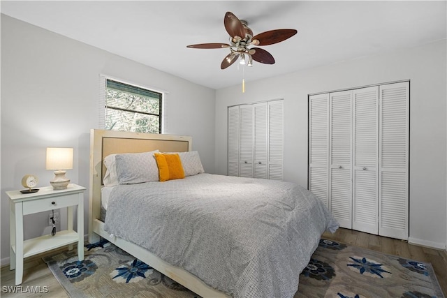 bedroom featuring ceiling fan, dark hardwood / wood-style flooring, and two closets