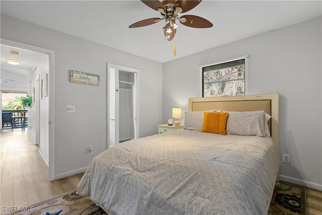 bedroom with multiple windows, hardwood / wood-style floors, ceiling fan, and a closet