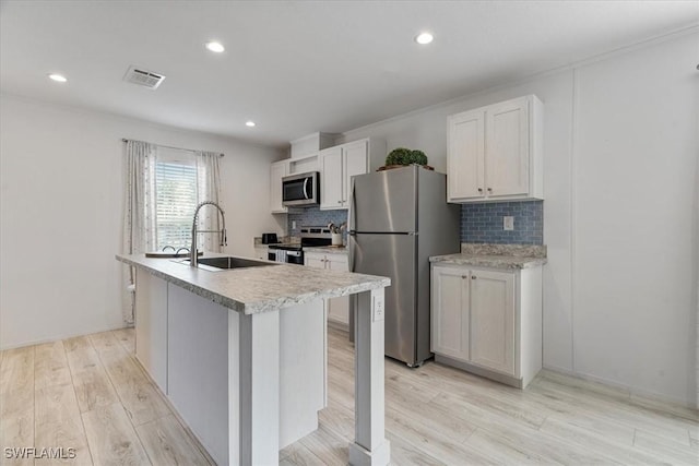 kitchen featuring white cabinetry, sink, a kitchen island with sink, stainless steel appliances, and light wood-type flooring