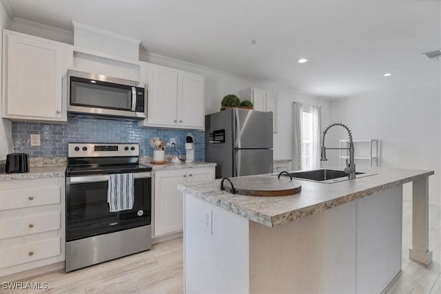 kitchen featuring appliances with stainless steel finishes, a kitchen island with sink, white cabinets, and backsplash