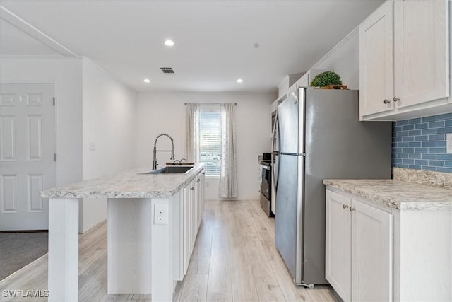 kitchen with sink, a kitchen island with sink, tasteful backsplash, light hardwood / wood-style floors, and white cabinets