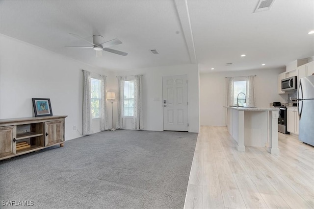 carpeted living room with sink and ceiling fan