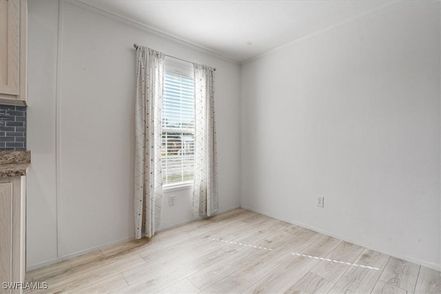 empty room with ornamental molding and light hardwood / wood-style flooring