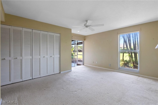 unfurnished bedroom featuring ceiling fan, light colored carpet, access to exterior, and a closet