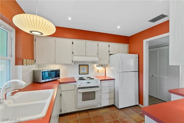 kitchen with sink, white appliances, light tile patterned floors, decorative backsplash, and decorative light fixtures