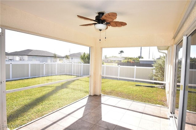 unfurnished sunroom featuring ceiling fan and plenty of natural light