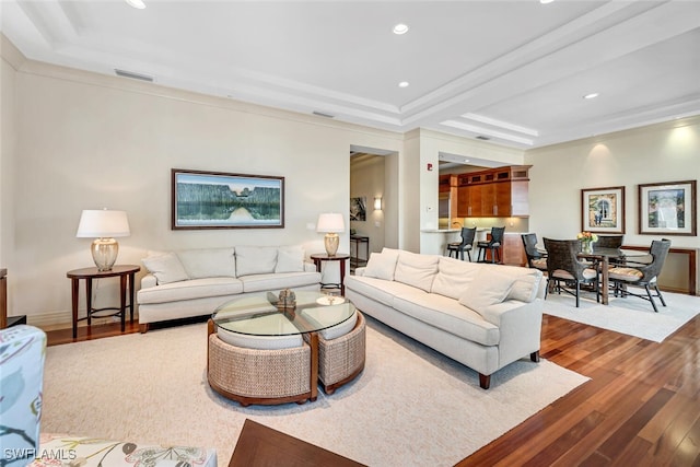 living room with a raised ceiling and light wood-type flooring