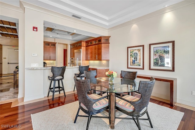 dining area with dark hardwood / wood-style flooring and a raised ceiling