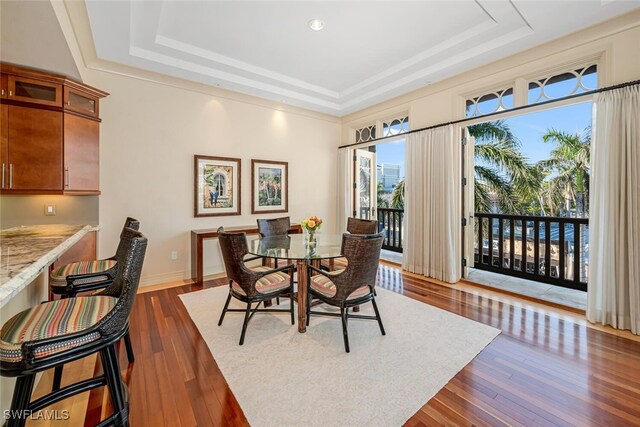 dining area with a raised ceiling and dark hardwood / wood-style flooring