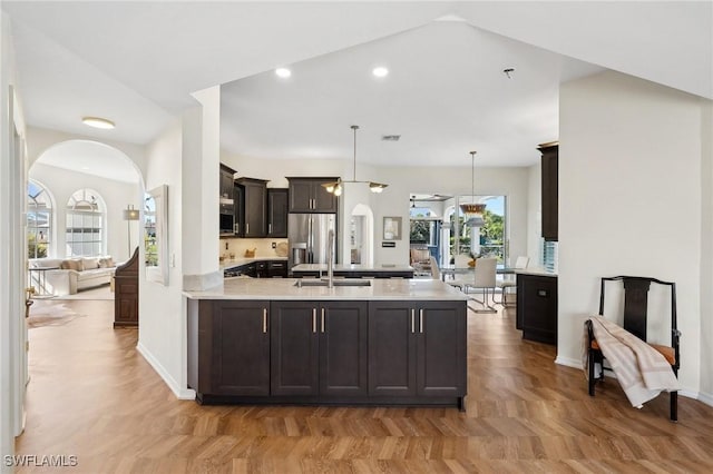 kitchen with stainless steel refrigerator with ice dispenser, dark brown cabinetry, sink, decorative light fixtures, and kitchen peninsula