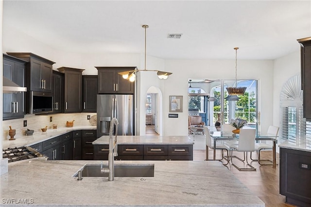 kitchen featuring sink, extractor fan, tasteful backsplash, stainless steel fridge with ice dispenser, and pendant lighting