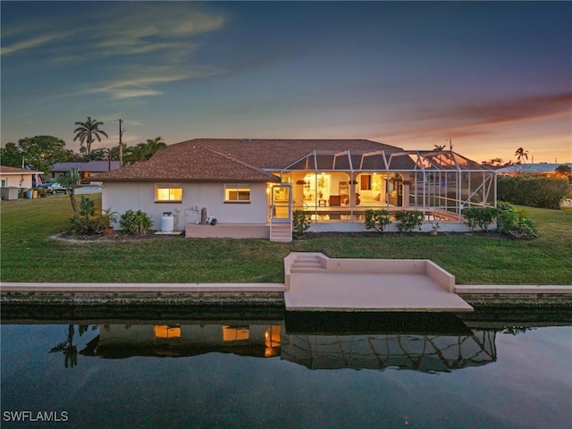 back house at dusk with a lanai, a lawn, and a patio