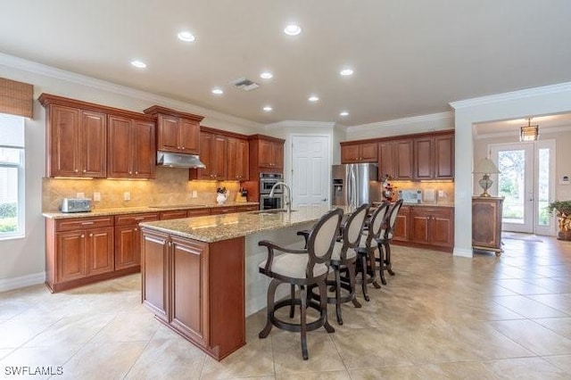 kitchen featuring sink, a kitchen breakfast bar, stainless steel appliances, tasteful backsplash, and an island with sink