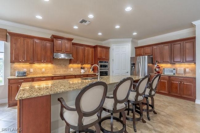 kitchen featuring stainless steel appliances, an island with sink, sink, and a breakfast bar area