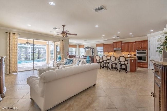 tiled living room with crown molding and ceiling fan