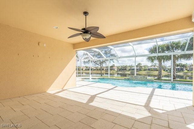 view of swimming pool featuring pool water feature, a patio area, a water view, a lanai, and ceiling fan