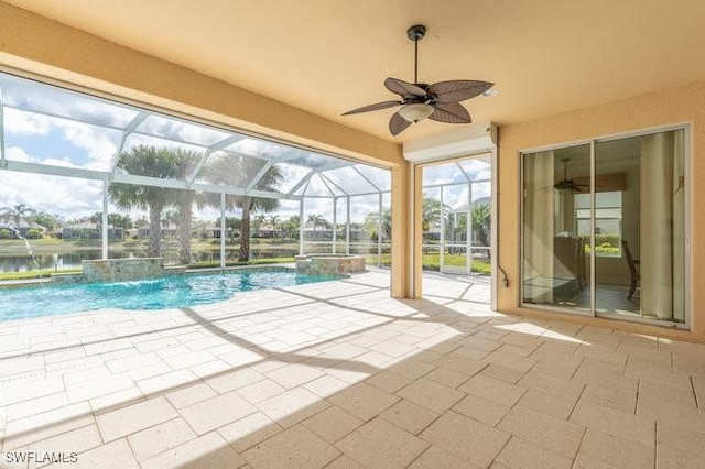 view of swimming pool with a patio, pool water feature, ceiling fan, glass enclosure, and a water view