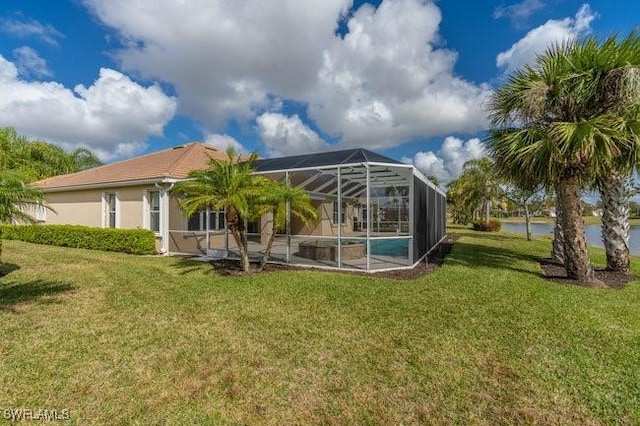 rear view of property with a water view, a yard, and glass enclosure