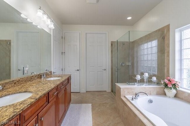 bathroom featuring shower with separate bathtub, a healthy amount of sunlight, vanity, and tile patterned floors