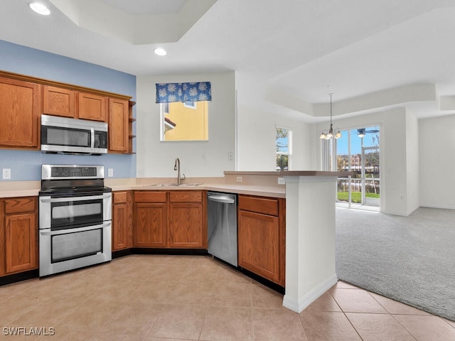 kitchen featuring sink, appliances with stainless steel finishes, a raised ceiling, kitchen peninsula, and light colored carpet