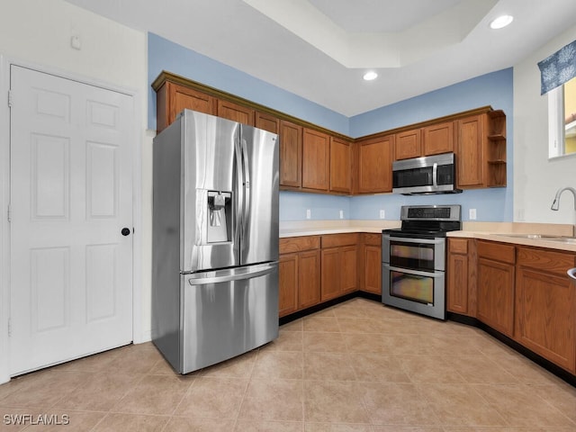 kitchen with stainless steel appliances, a raised ceiling, sink, and light tile patterned floors