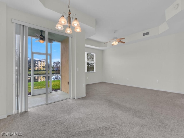 unfurnished room with a water view, a tray ceiling, carpet flooring, and ceiling fan with notable chandelier