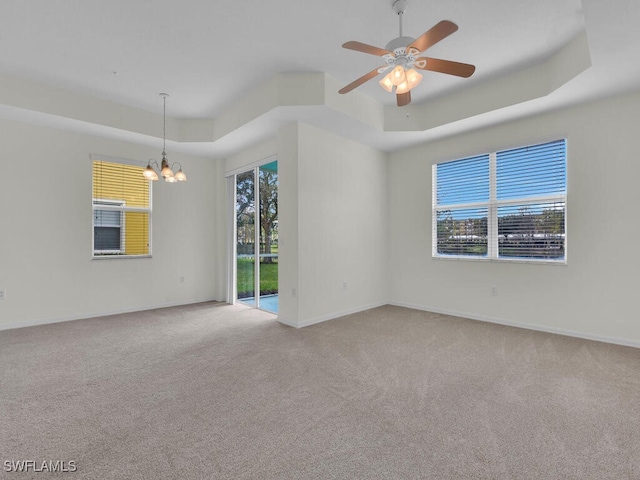 unfurnished room with ceiling fan with notable chandelier, a raised ceiling, and carpet