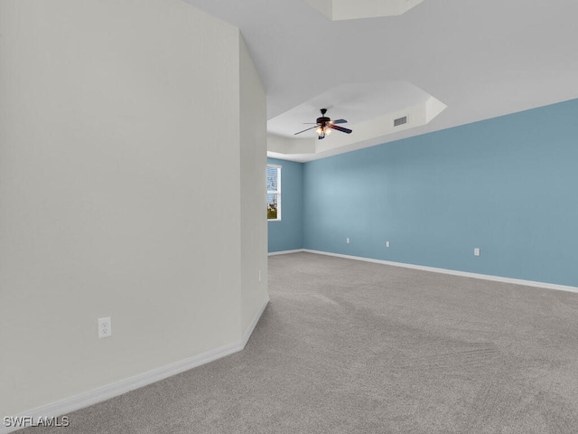 carpeted empty room with a tray ceiling and ceiling fan