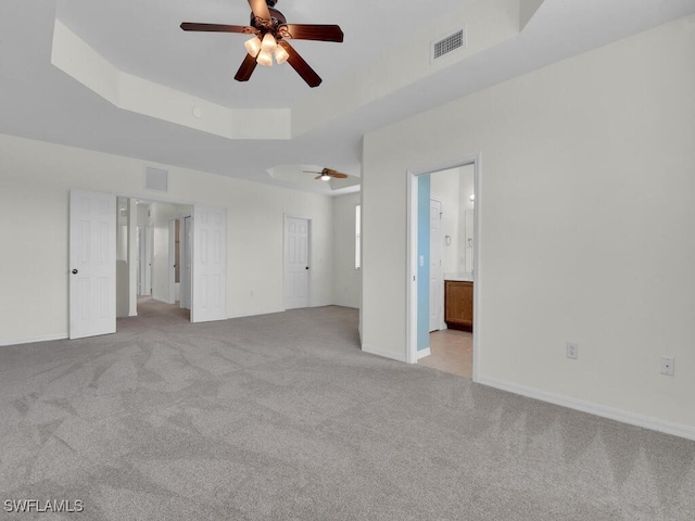 carpeted empty room with a tray ceiling and ceiling fan