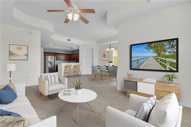 living room featuring light colored carpet, ceiling fan with notable chandelier, and a wealth of natural light