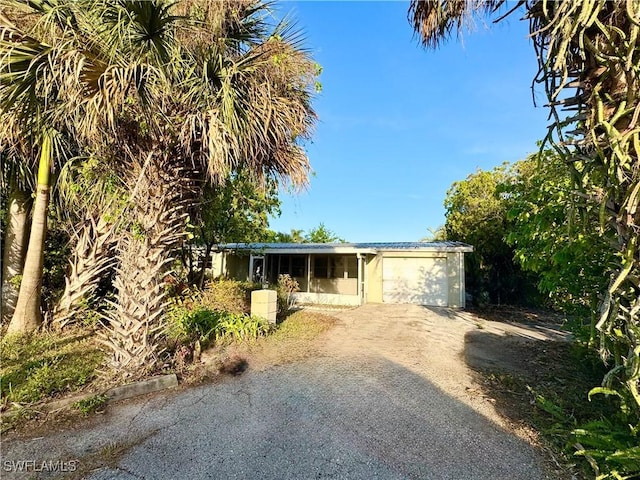 ranch-style home featuring driveway, a garage, and metal roof