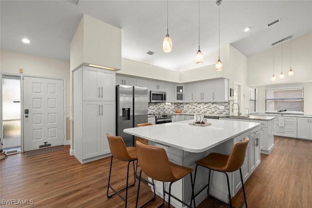 kitchen with sink, dark wood-type flooring, stainless steel appliances, tasteful backsplash, and a kitchen island