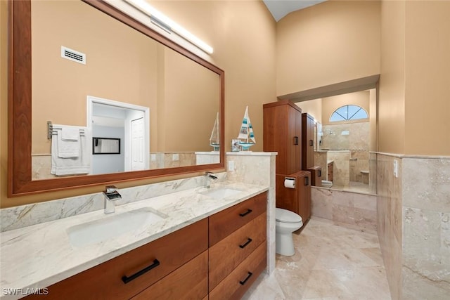 bathroom featuring vanity, toilet, a high ceiling, and a tile shower